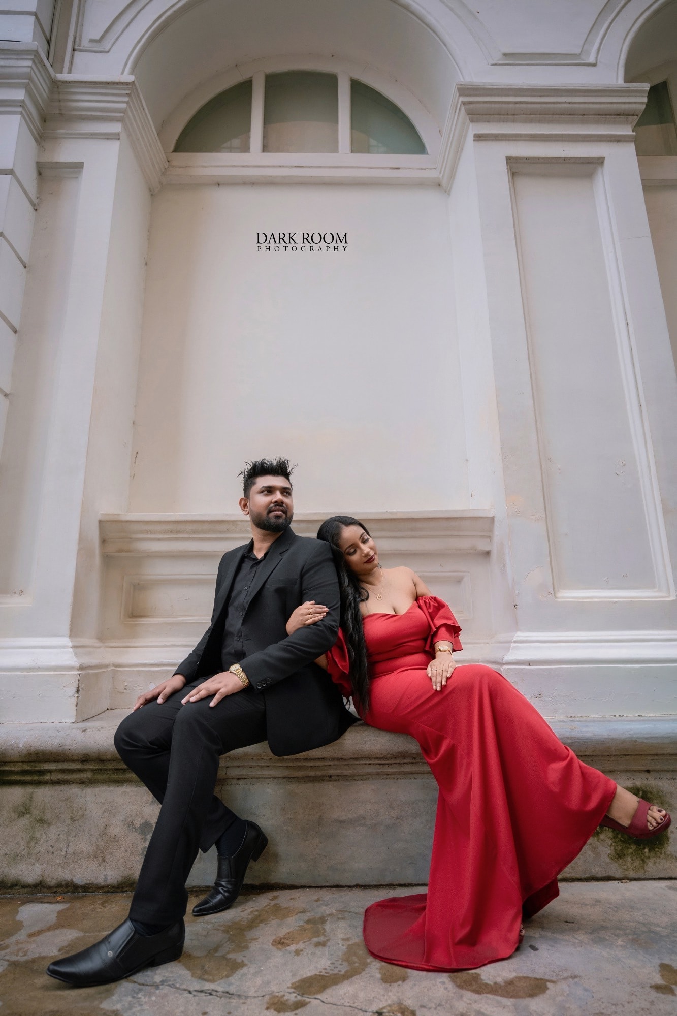 Ashan and Oshini seated back to back on a stone bench